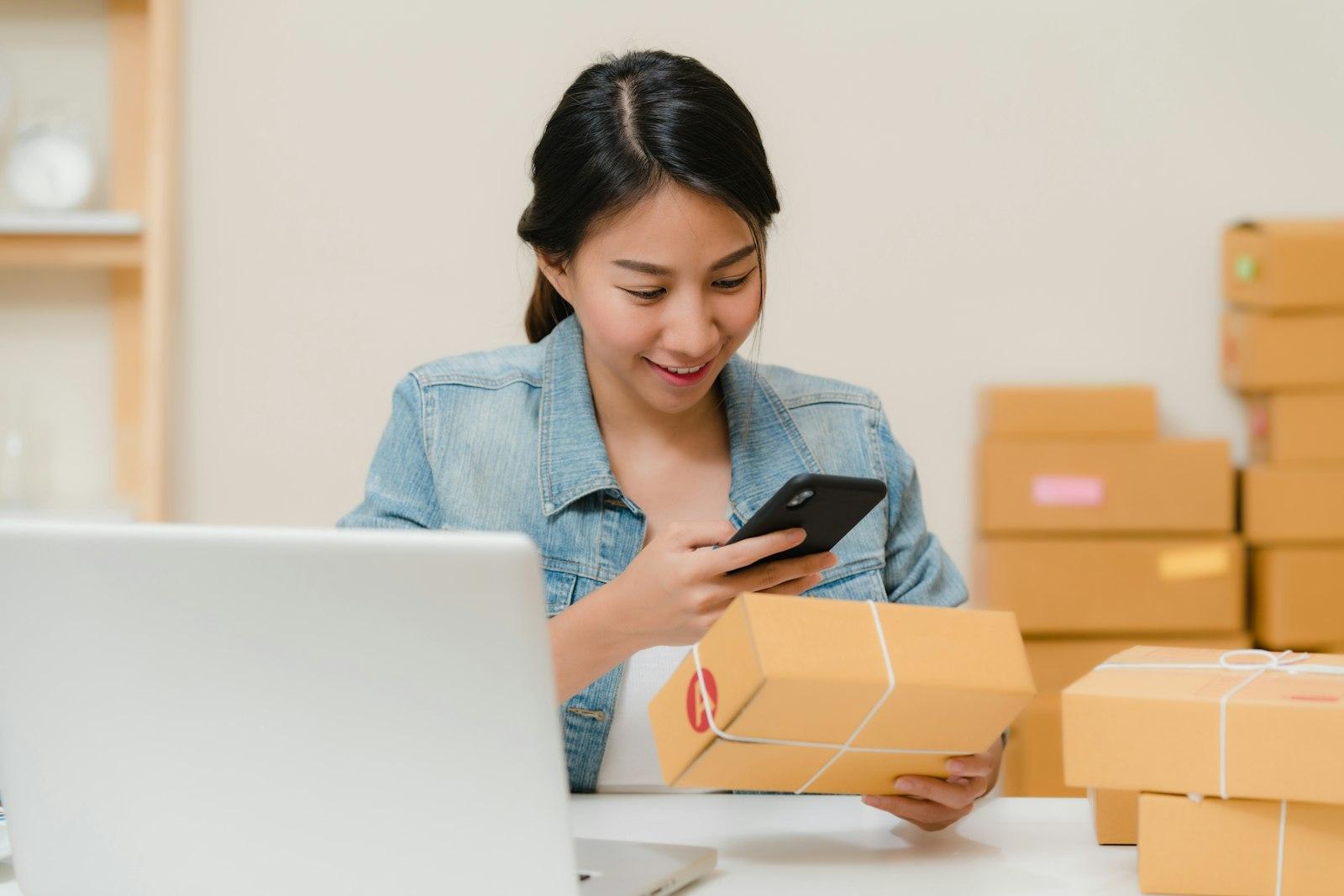 Een webshopeigenaar met een telefoon tussen de pakketjes